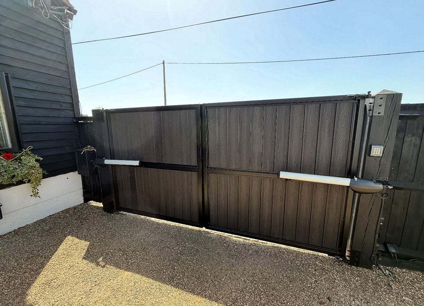Dark double swing gates with two operator arms and a keypad mounted on the right-hand post