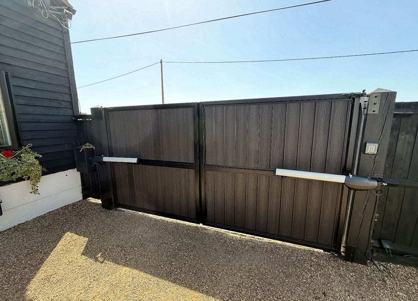 Dark double swing gates with two operator arms and a keypad mounted on the right-hand post